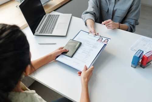 Woman,Applying,For,Visa,At,Table