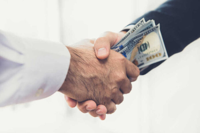 Businessmen,Making,Handshake,With,Money,In,Hands,-,Bribery,And
