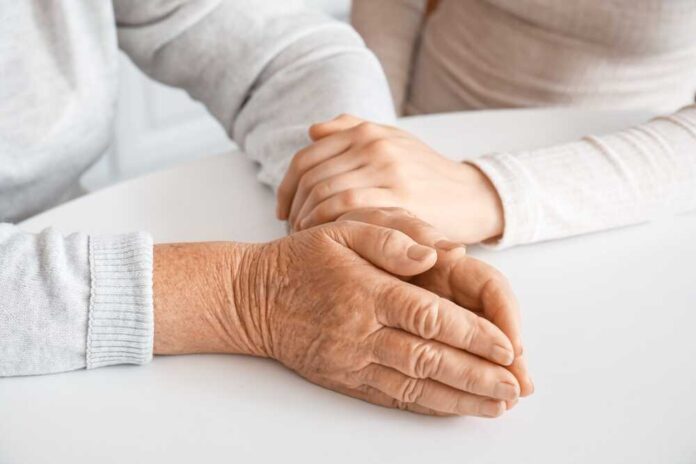 Young,Woman,With,Her,Grandmother,Holding,Hands,At,Table,In