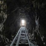Dark tunnel leading to bright exit with tracks