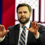 I dont know who this is. Man speaking with hands raised.