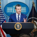 Defense Secretary’s SHOCK Move Against Woke Elites Man speaking at podium with flags in background
