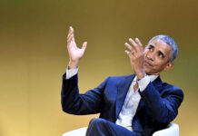 A man in a suit gesturing while speaking at an event