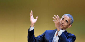 A man in a suit gesturing while speaking at an event