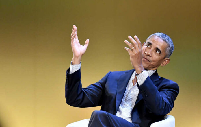A man in a suit gesturing while speaking at an event