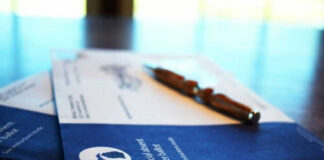 Absentee ballot envelopes with pen on table.