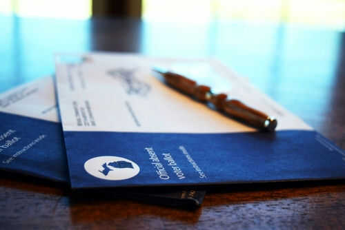 Absentee ballot envelopes with pen on table.
