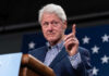 Clintons’ NYC ‘Bump’ – The Conspiracy Theories Begin Man in suit gesturing during speech with stars backdrop