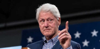 Man in suit gesturing during speech with stars backdrop