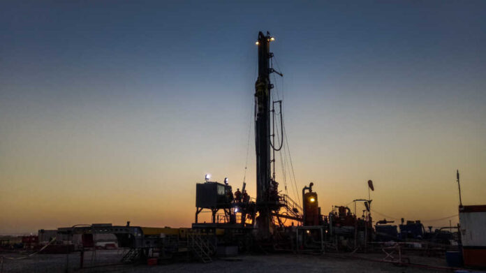 drilling rig activity_1172833099.jpg Drilling rig silhouetted against a sunset with workers visible