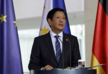 Man in suit speaking near European Union flags