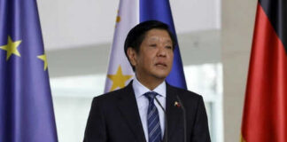 Man in suit speaking near European Union flags