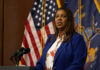 Woman speaking at a podium with flags behind her