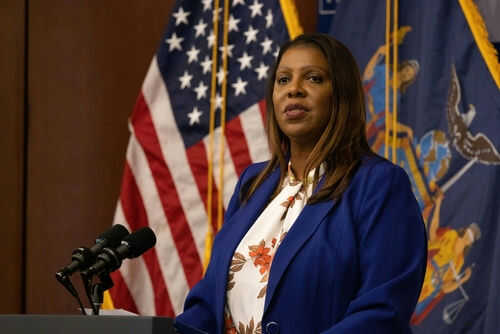 Woman speaking at a podium with flags behind her