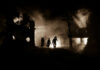 Silhouettes walking through smoky destroyed urban landscape night