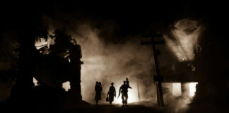 Silhouettes walking through smoky destroyed urban landscape night