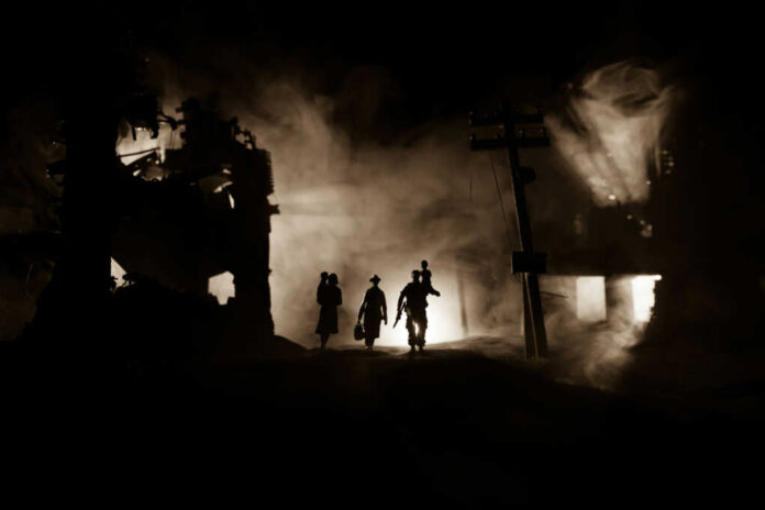 Silhouettes walking through smoky destroyed urban landscape night