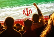 Crowd of people with their hands raised in front of the Iranian flag