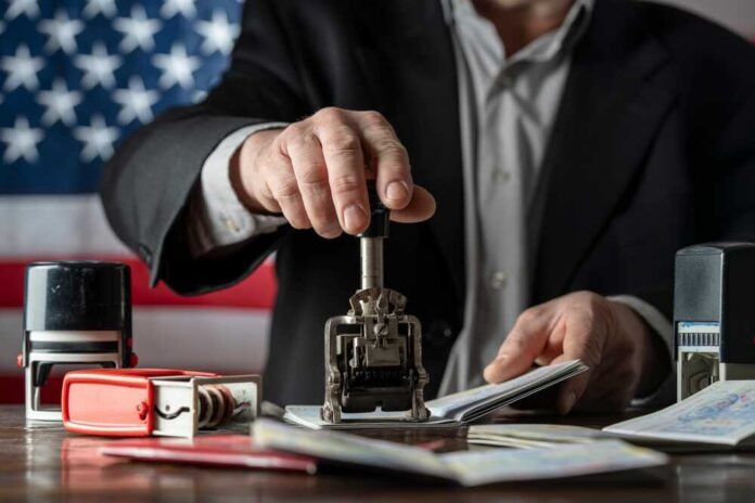 A person stamping passports on a desk with various stamps and documents