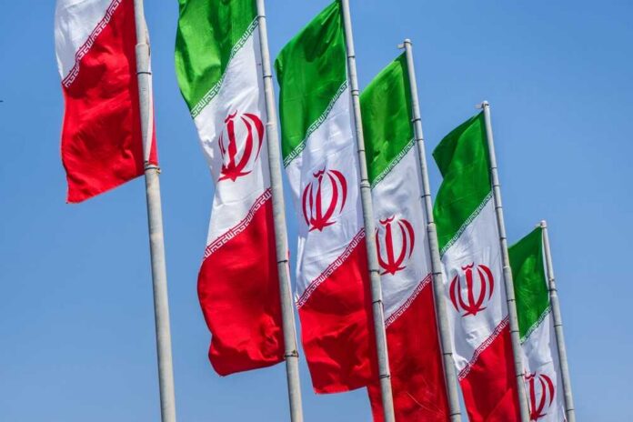 Multiple Iranian flags waving against a clear blue sky