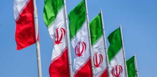 Multiple Iranian flags waving against a clear blue sky