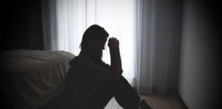 A silhouette of a woman sitting on the floor, looking contemplative near a window