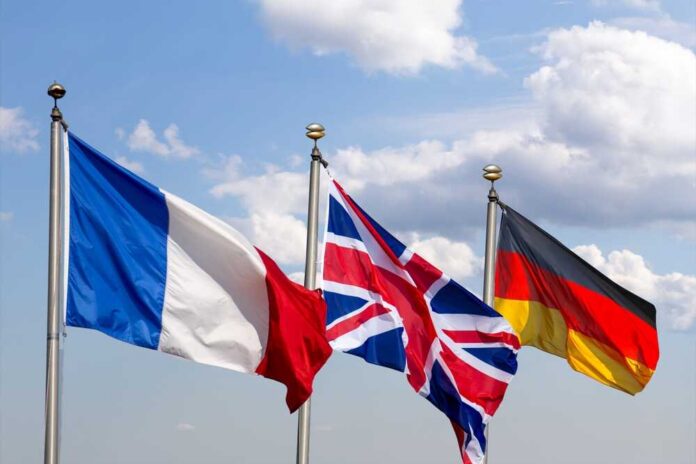 Flags of France, the United Kingdom, and Germany waving against a blue sky