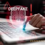 A hand interacting with a laptop displaying a deepfake warning