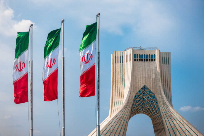 shutterstock_505715608.jpg Three Iranian flags in front of the Azadi Tower against a blue sky