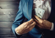Person in a suit placing cash into their jacket pocket