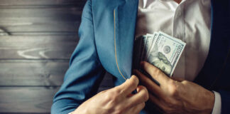 Person in a suit placing cash into their jacket pocket