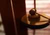 Wooden gavel on a reflective surface.