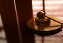 Wooden gavel on a reflective surface.