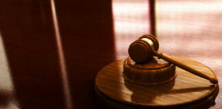 Wooden gavel on a reflective surface.