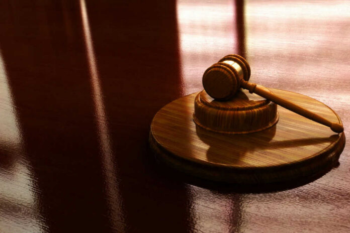 Wooden gavel on a reflective surface.