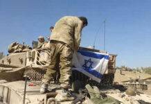 Soldiers setting Israeli flag on military vehicle tank