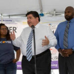 Pritzker SLAMS Trump – Claims National Security THREAT Three people speaking at a promotional event.
