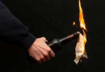 Person holding molotov cocktail with flame burning cloth