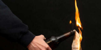 Person holding molotov cocktail with flame burning cloth