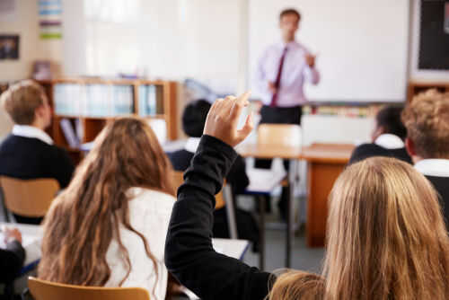 school_769521358 Classroom with student raising hand teacher speaking front