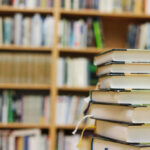 Stack of books in a library with shelves in the background