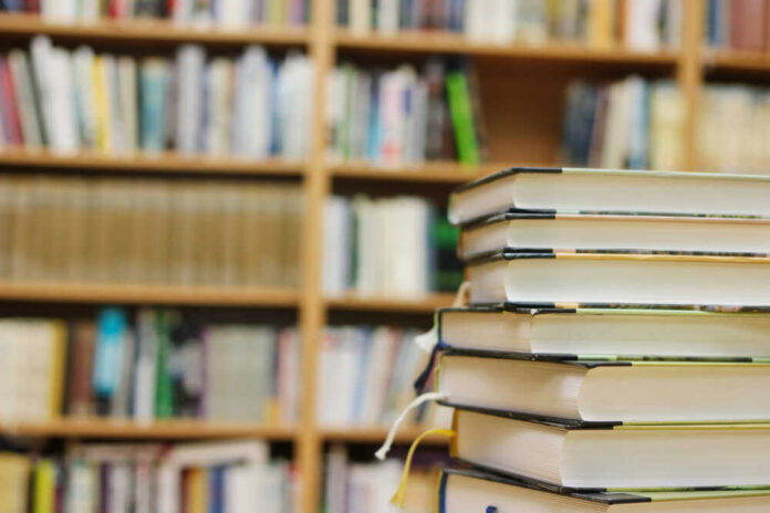 Stack of books in a library with shelves in the background