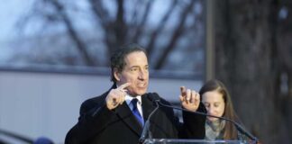 A man speaking passionately at a podium during an outdoor event