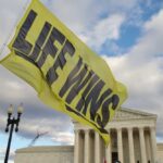 A large yellow flag with the words 'LIFE WINS' waving in front of the Supreme Court building