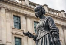 NHS Nurse’s Career At Risk Over Pronoun Dispute Bronze statue of a woman holding a bird in an urban environment