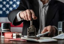 A person stamping passports on a desk with various stamps and documents