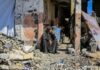 A woman sitting among rubble outside a damaged building