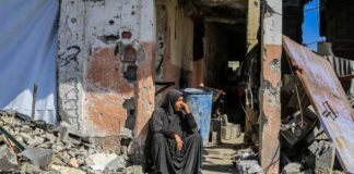A woman sitting among rubble outside a damaged building