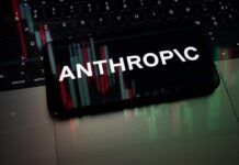 Smartphone displaying the word 'ANTHROPIC' over a background of financial graphs