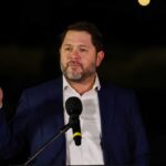 Man in a suit delivering a speech at an outdoor event